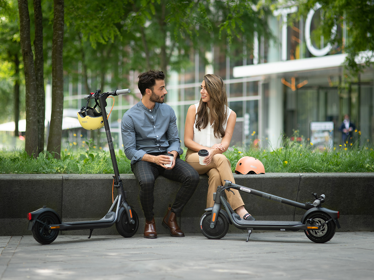 Ninebot KickScooter F20D-F25E-F30_Lifestyle picture_Man and woman sitting_One folded and unfolded KickScooters.jpg